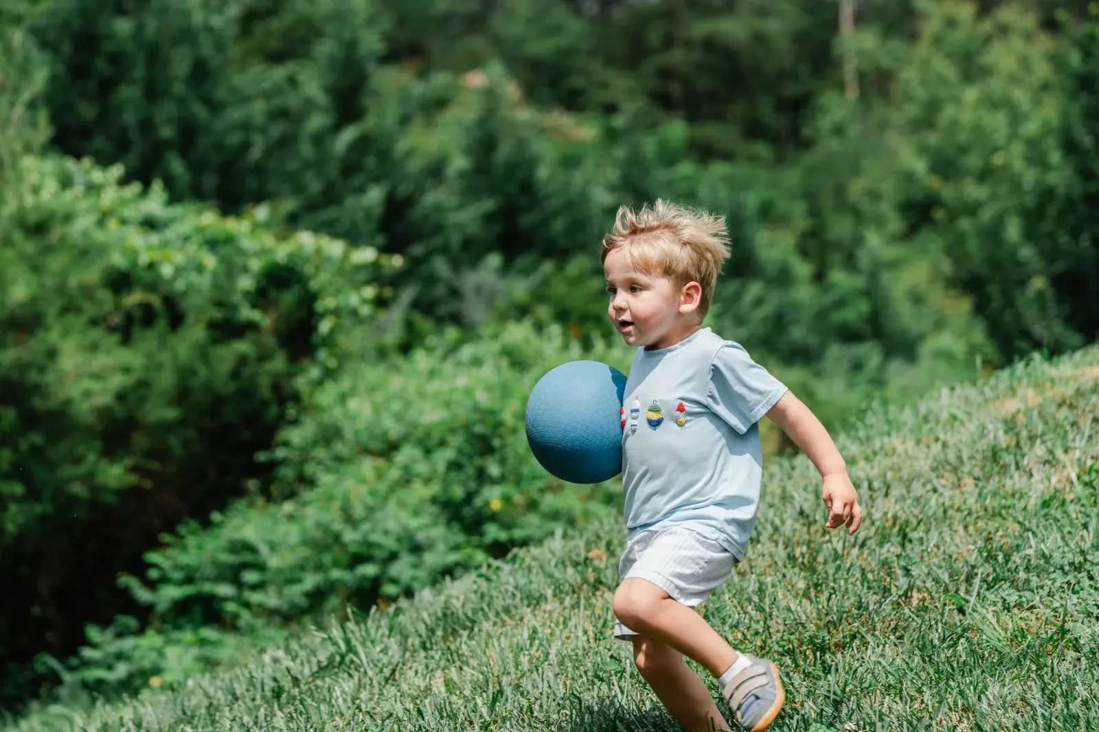 A young child running outdoors with a ball
