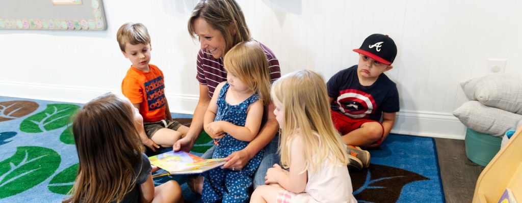 A woman sits and reads to children.